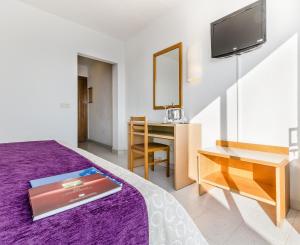 1 dormitorio con cama morada y escritorio en Gran Sol Hotel en San Pol de Mar