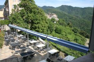 a balcony with tables and chairs and mountains in the background at Le Refuge Orezza in Piedicroce