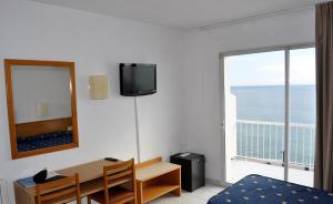 Cette chambre comprend une chambre dotée d'un bureau et d'un miroir. dans l'établissement Gran Sol Hotel, à San Pol de Mar