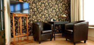 アントワープにあるBed & Breakfast Exterlaerのテレビの前に座る黒い革張りの椅子2脚