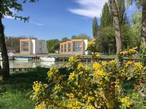 a house on the water with flowers in the foreground at Akvárium Apartmanházak in Keszthely