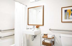 Baño blanco con lavabo y espejo en The Laurel Inn, part of JdV by Hyatt, en San Francisco