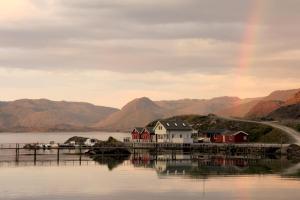 einen Regenbogen über einem See mit Häusern und einem Dock in der Unterkunft Nordkapp Camping in Honningsvåg