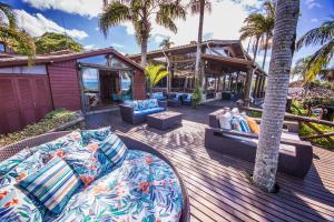 a deck with two couches and palm trees at Vida Sol e Mar Ecoresort in Praia do Rosa