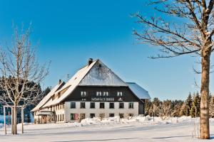 um grande celeiro preto e branco na neve em Gasthaus Kalte Herberge em Vöhrenbach