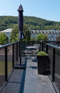- une terrasse avec un parasol, une table et une table dans l'établissement RESIDENCE AUX DEUX PICS - Tucou et Monné, à Bagnères-de-Bigorre