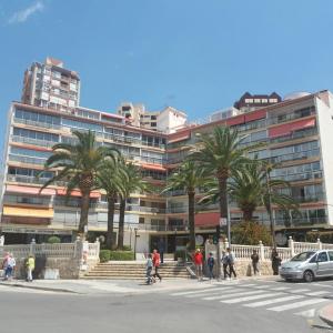personnes marchant devant un grand bâtiment avec des palmiers dans l'établissement Seimar68, à Benidorm