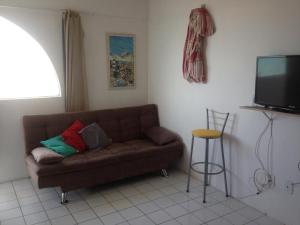 a living room with a brown couch and a television at Flat em Sao Jose da Coroa Grande in São José da Coroa Grande