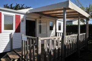 a white tiny house with a porch and an awning at Camping Les Perouses in Saint-Clément-des-Baleines