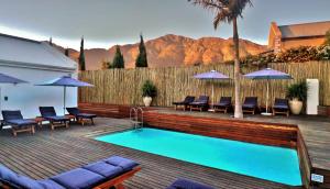a swimming pool with chairs and umbrellas on a deck at theLAB Franschhoek in Franschhoek