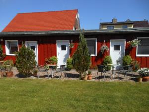 une maison rouge avec des chaises et des tables dans une cour dans l'établissement Alte Schmiede Putbus, à Putbus