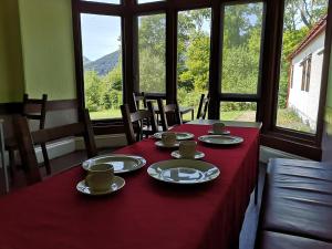 a table with a red table cloth with cups and saucers at Rowardennan Youth Hostel in Rowardennan