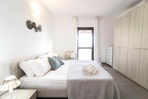 una camera bianca con letto e armadio di Homey Experience - Emerald Valley Apartment a Porto Cervo