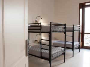 レッチェにあるLobby Collective Hostel - Lecceの窓付きの客室で、黒い二段ベッド2台が備わります。