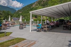 un grupo de personas sentadas en mesas bajo un pabellón cerca de una piscina en Savoy Hôtel, en Brides-les-Bains