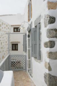 a white room with a stone wall with a gate at The Pulse Residence Astypalea in Astypalaia