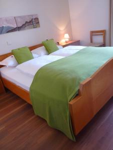 ein Schlafzimmer mit einem großen Bett mit grüner Bettwäsche in der Unterkunft Gasthof Albergo Kreuzwirt in Völs am Schlern