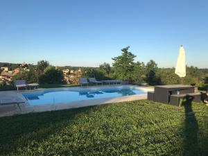 a pool with chairs and a table and an umbrella at ConfinedeiSanti B&B in Moriondo Torinese