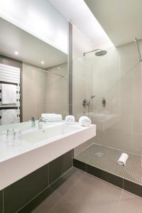 La salle de bains est pourvue d'un lavabo et d'un grand miroir. dans l'établissement Hôtel de l'Europe by HappyCulture, à Strasbourg