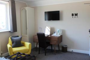a hotel room with a desk and a chair and a television at Badgers Mount Hotel in Earl Shilton