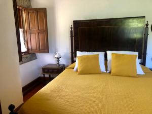 1 dormitorio con 1 cama grande con almohadas amarillas en Agro-Turismo - Quinta do Pinheiro, en Cavadoude