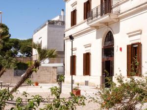 a white building with a palm tree in front of it at Lobby Collective Hostel - Lecce in Lecce