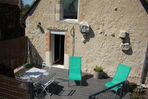 um pátio com cadeiras, uma mesa e um edifício em Gite du Moulin de Balzac em Artannes-sur-Indre