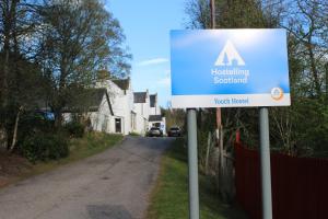 una señal al costado de una carretera en Cairngorm Lodge Youth Hostel, en Loch Morlich