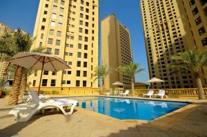 a pool with chairs and an umbrella and buildings at JBR The Walk Rimal - 4-Bedroom Suite Full Sea View High floor in Dubai