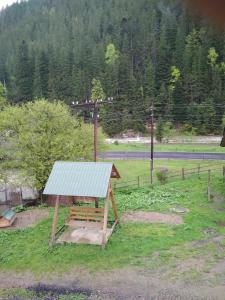 a wooden bench with a green roof in a field at Na Horbyku in Tatariv