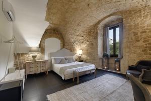 een slaapkamer met een bed en een stenen muur bij Itria Palace in Ragusa