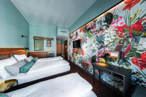 Dos camas en una habitación con una gran pared floral. en Maison Schiller by DesignCity Hotels, en Múnich
