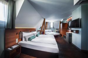 1 dormitorio con 1 cama blanca grande y TV en Maison Schiller by DesignCity Hotels, en Múnich