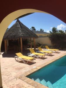 a group of yellow lounge chairs and a swimming pool at Casa Opal in Palm-Eagle Beach