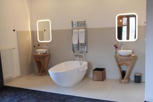 uma casa de banho com uma banheira grande, 2 lavatórios e uma banheira. em Eclosion Château Hôtel & Restaurant em Saint-Paul-en-Jarez