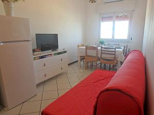 ein Wohnzimmer mit einem roten Sofa und einer Küche in der Unterkunft Pagoda 15 - Appartamento fronte mare con servizio spiaggia in Lido di Pomposa