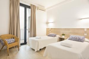 a hotel room with two beds and a chair at BcnStop Parc Güell in Barcelona