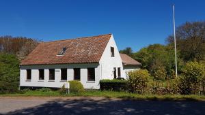 a white house with a brown roof on a street at Sænehus Husmandssted in Allinge