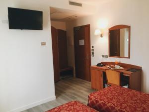 a hotel room with a desk and a bed and a table at Hotel Alla Croce in Negrisia