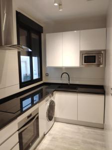 een keuken met witte kasten en een wasmachine bij Unique apartment in Málaga city center with pool in Málaga