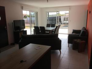 een woonkamer met een bank en een tafel met stoelen bij maison individuelle 500 m de la mer in Agon Coutainville