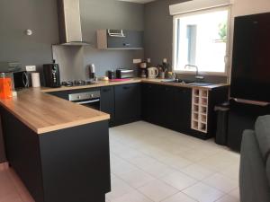 eine Küche mit schwarzen Schränken, einem Waschbecken und einem Fenster in der Unterkunft maison individuelle 500 m de la mer in Agon Coutainville