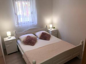 1 dormitorio con 1 cama blanca y 2 mesitas de noche en Apartments Vrdoljak, en Pag