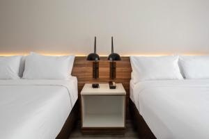 two beds sitting next to each other with a table at Wyndham Garden Ft Lauderdale Airport & Cruise Port in Dania Beach