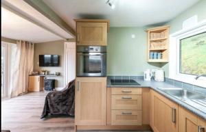 a kitchen with a sink and a stove top oven at Crofters Cabin in Caernarfon