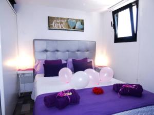 um quarto com uma cama com balões e lençóis roxos em Mi Abeto em Tías