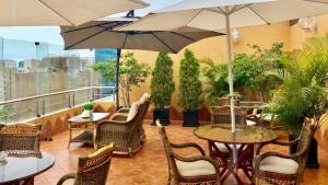 un patio con mesas, sillas y sombrillas en el balcón en Apart Hotel San Martin en Lima