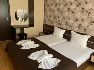 two beds in a hotel room with towels on them at Family Hotel Piter in Golden Sands