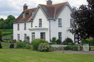 una gran casa blanca con un patio verde en Lower Bryanston Farm en Blandford Forum