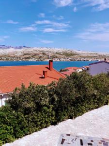 a building with a red roof and a body of water at Apartments Vrdoljak in Pag